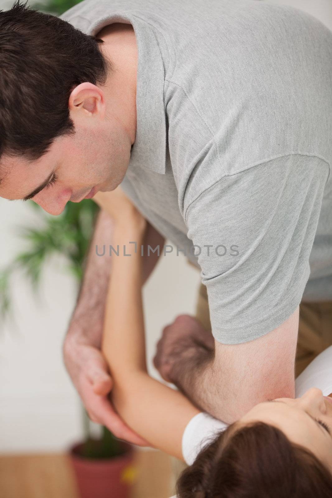 Serious osteopath placing his elbow of the shoulder of a patient by Wavebreakmedia