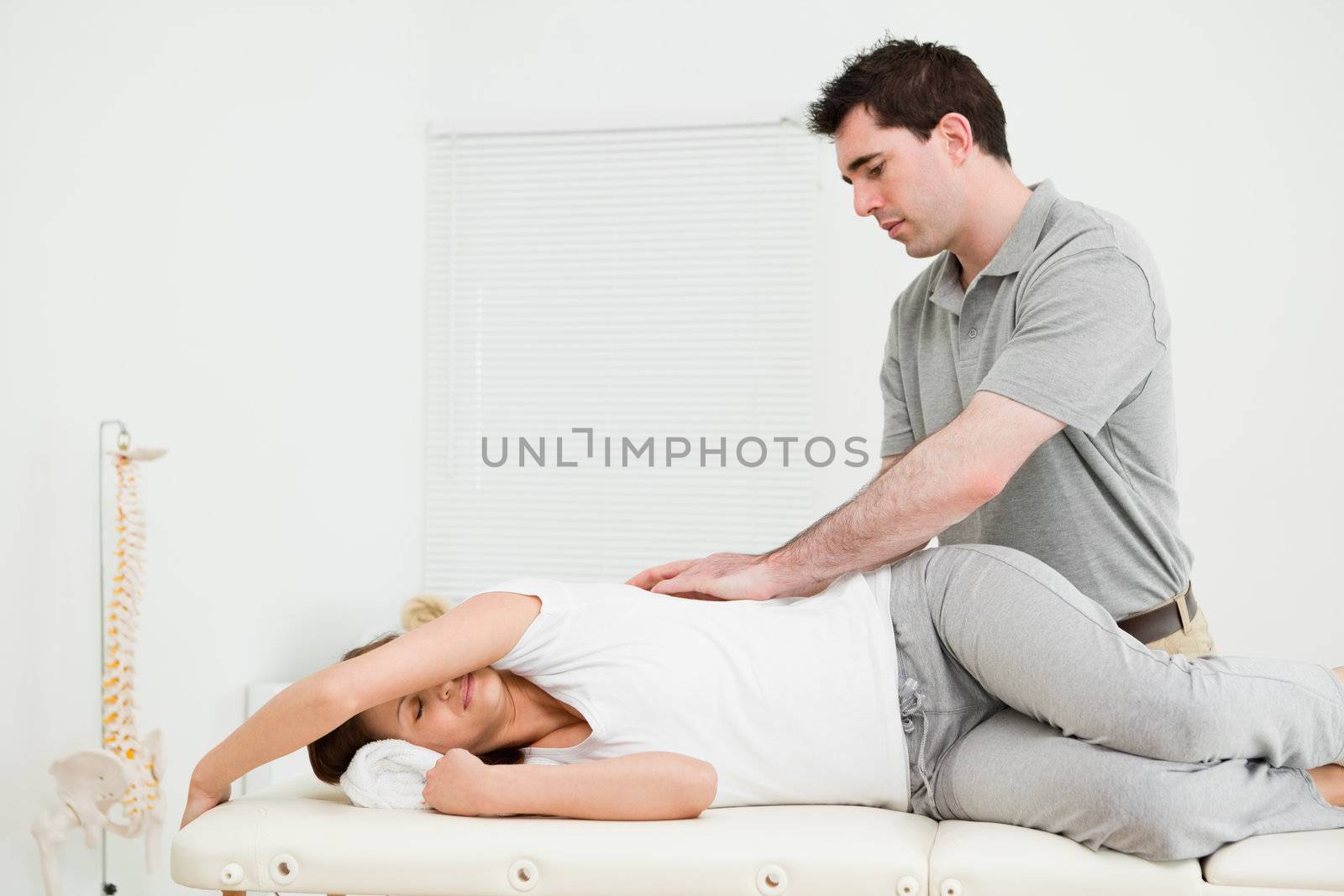 Brunette woman lying on the side while being massaged in a medical room