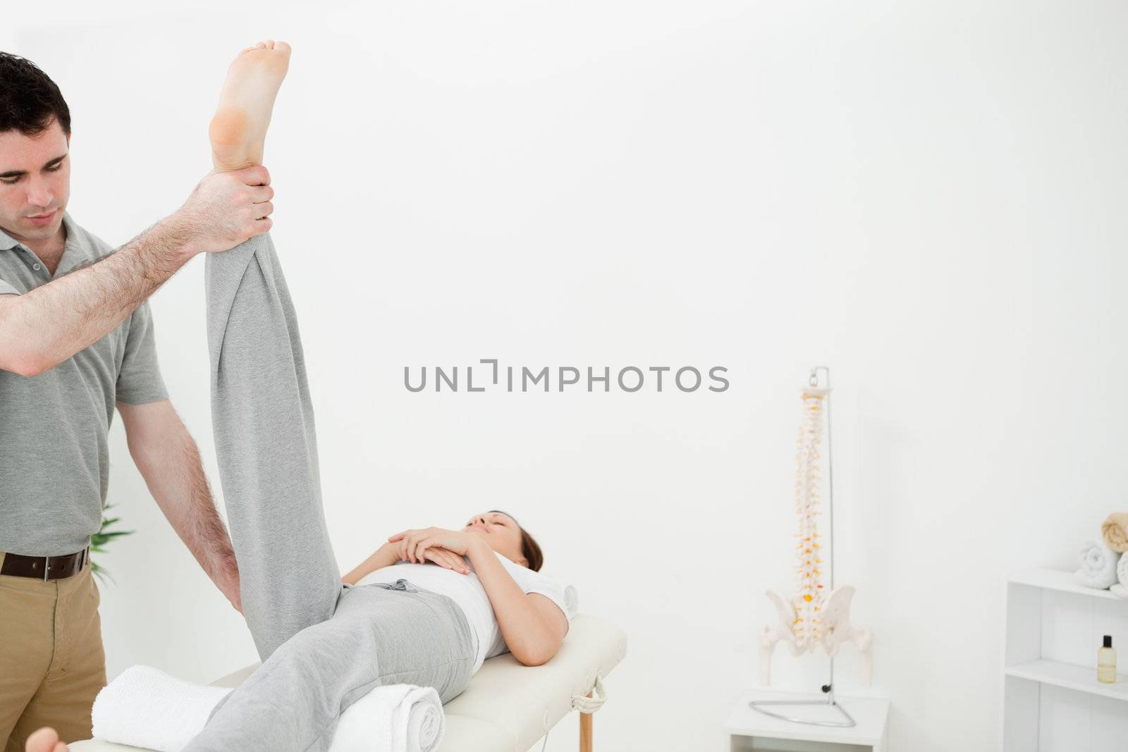 Physiotherapist raising the leg of a woman in a room