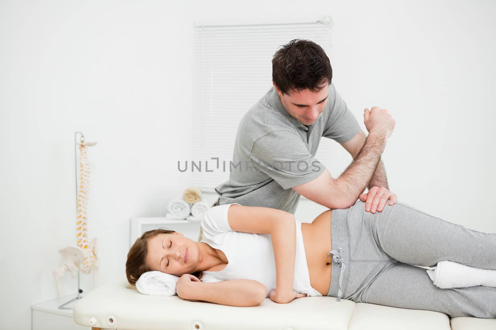 Doctor using his elbow to massage the hip of a woman by Wavebreakmedia