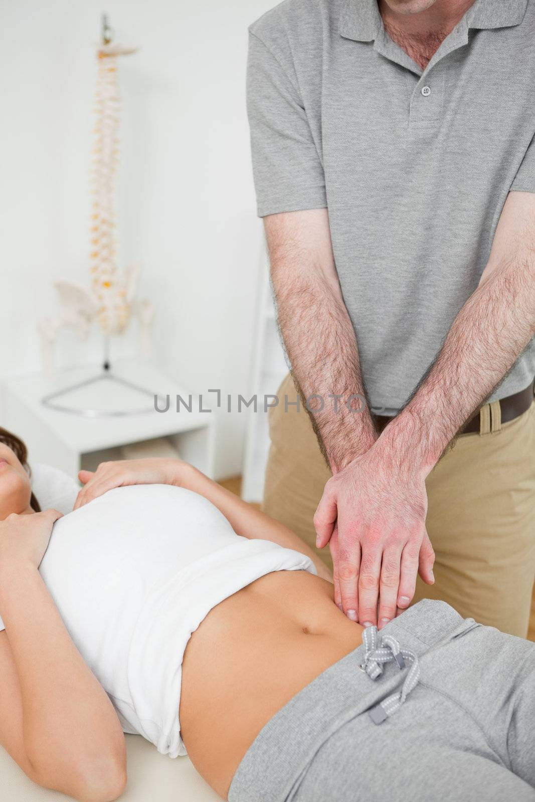 Doctor examining the painful abdomen of a woman in his office