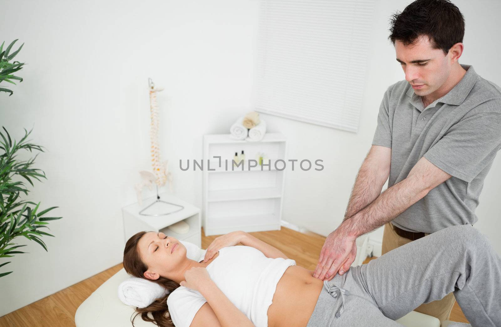 Osteopath touching the hip of a woman with his fingertips by Wavebreakmedia