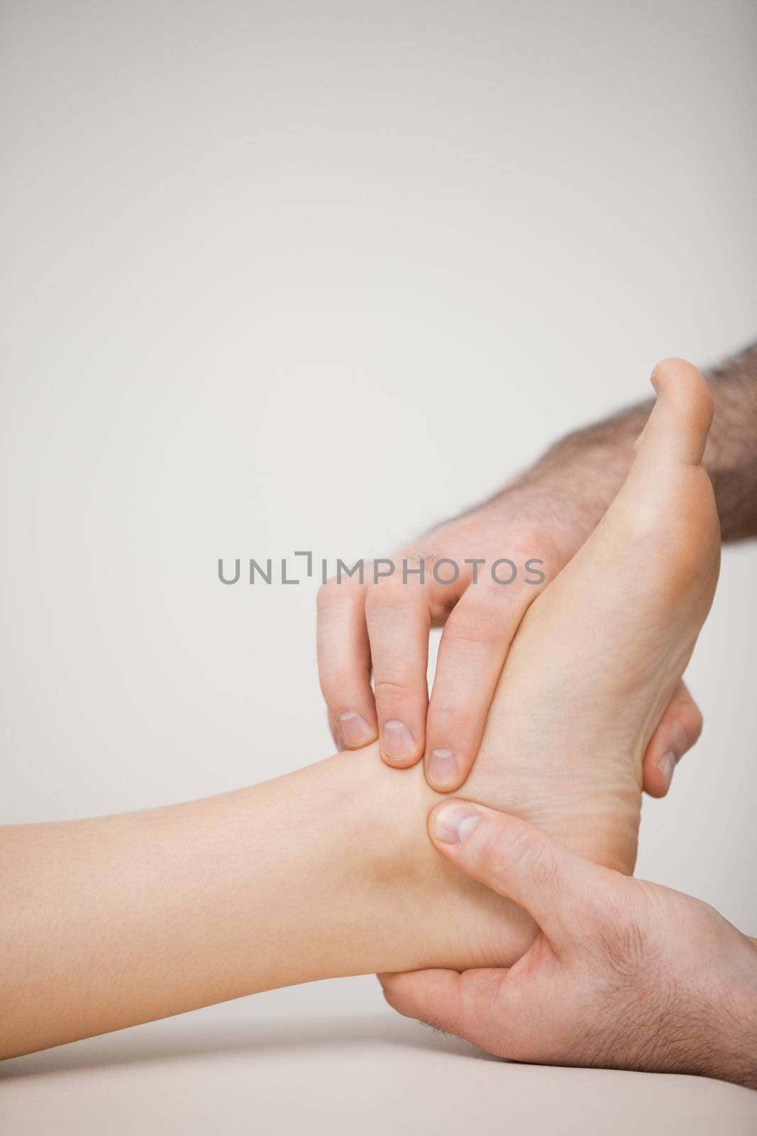 Doctor massaging the side of a foot in a medical room