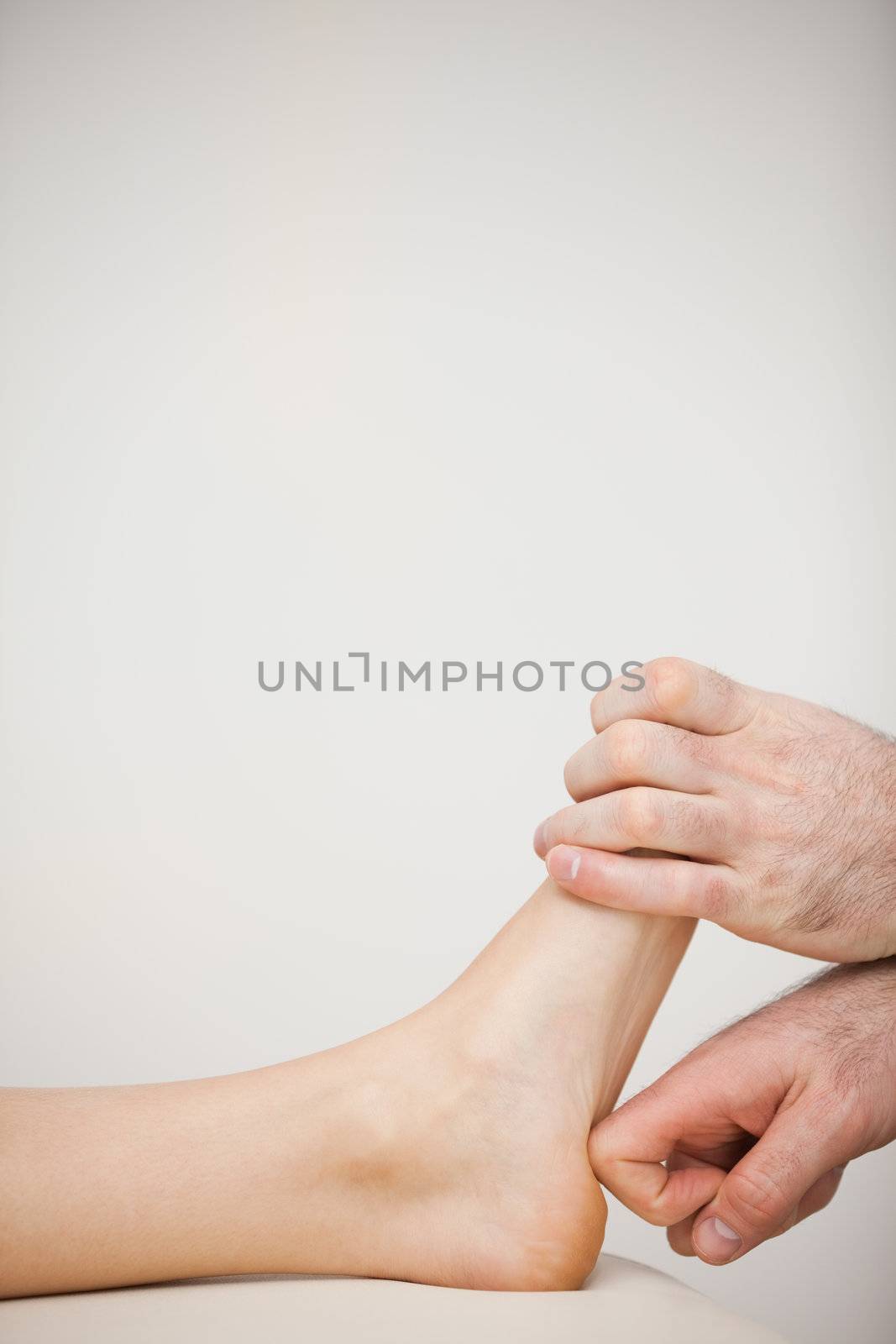 Chiropodist using his index finger to massage a foot in a medical room