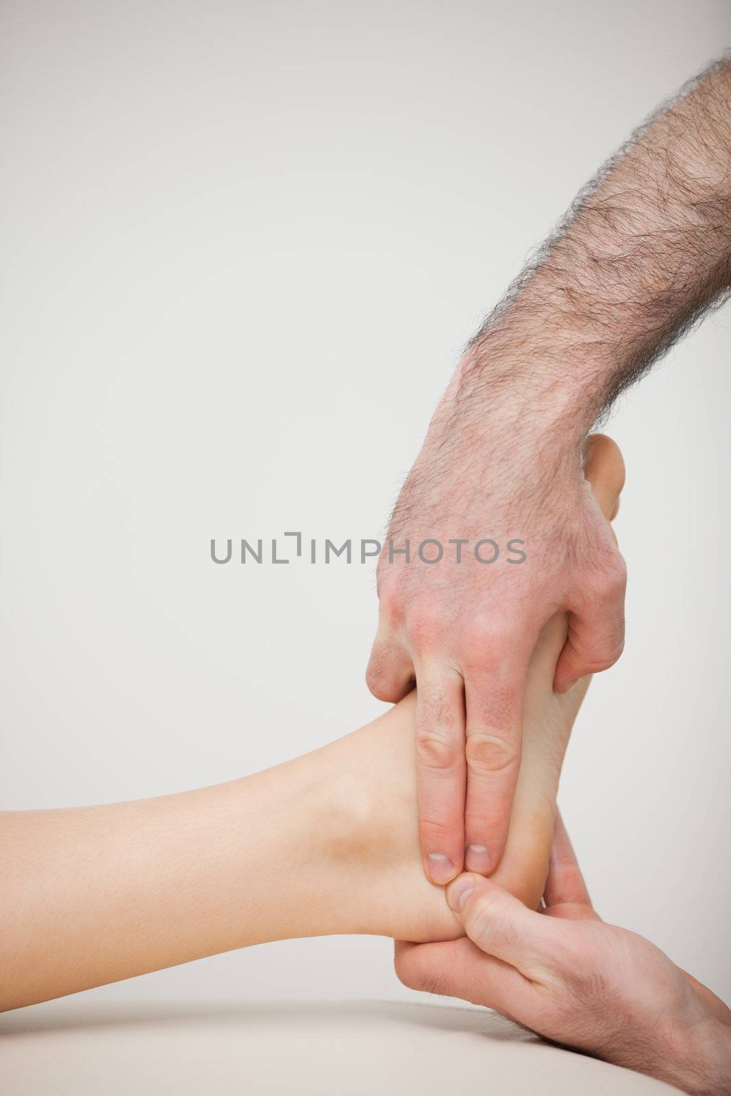 Two fingers pressing the Achilles tendon of a patient by Wavebreakmedia