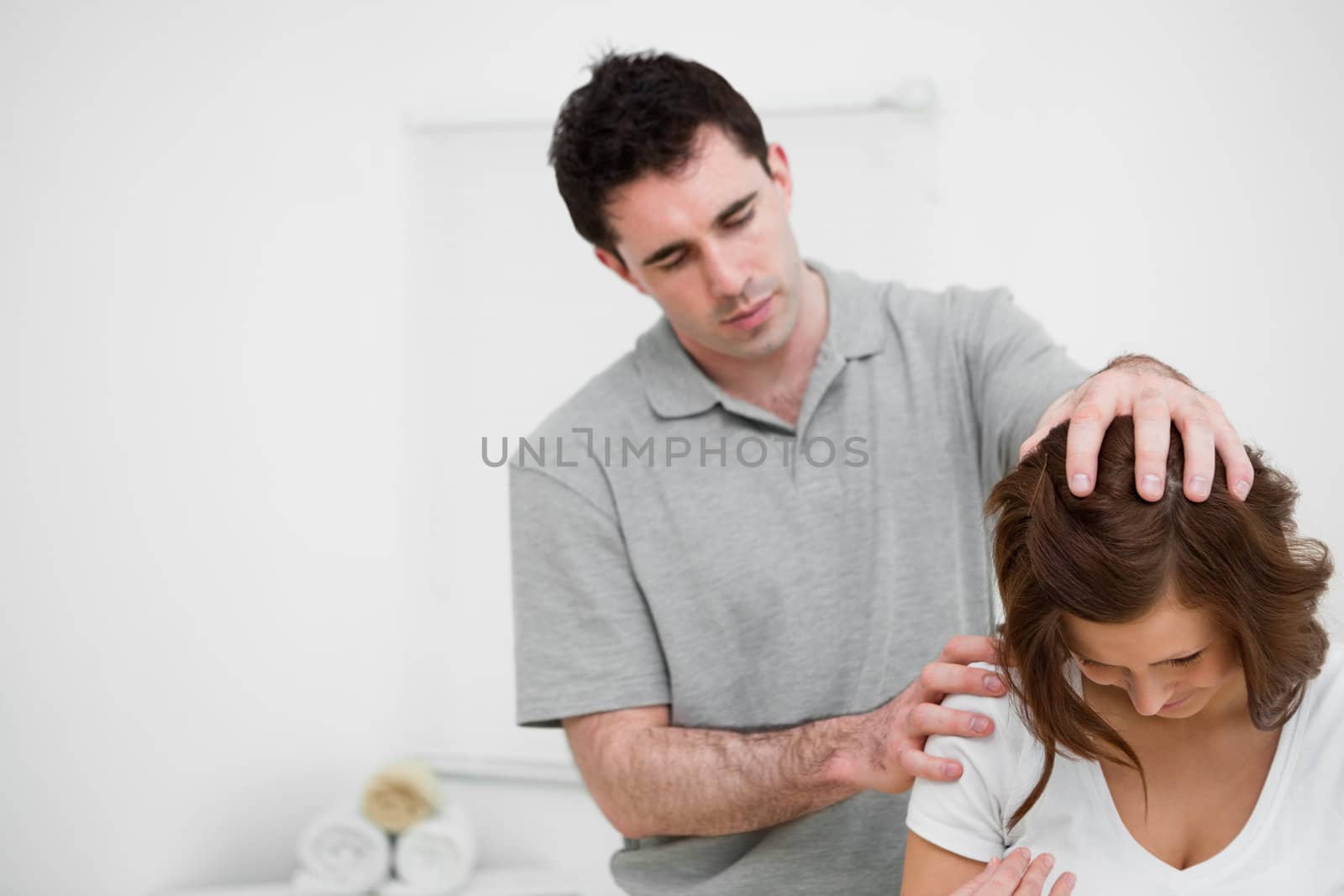 Physiotherapist moving the head of a brunette woman in a medical room