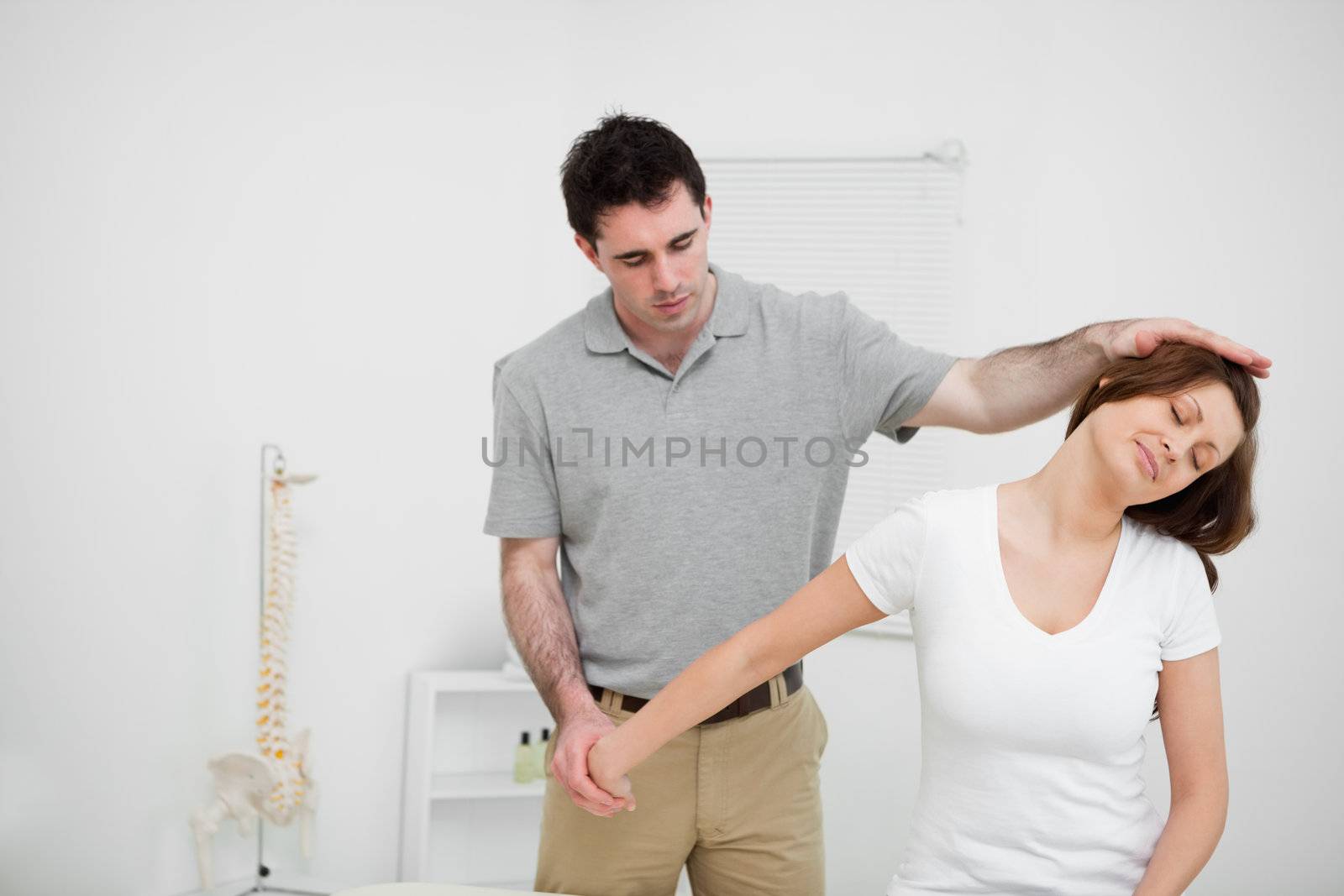 Osteopath stretching the arm of a woman in a medical room