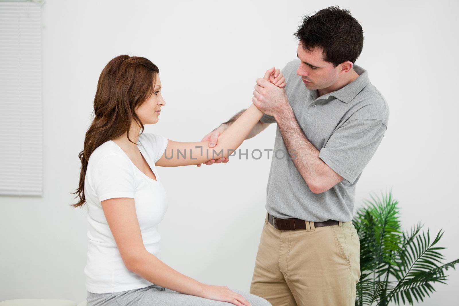 Serious practitioner touching the elbow of a woman in a medical room