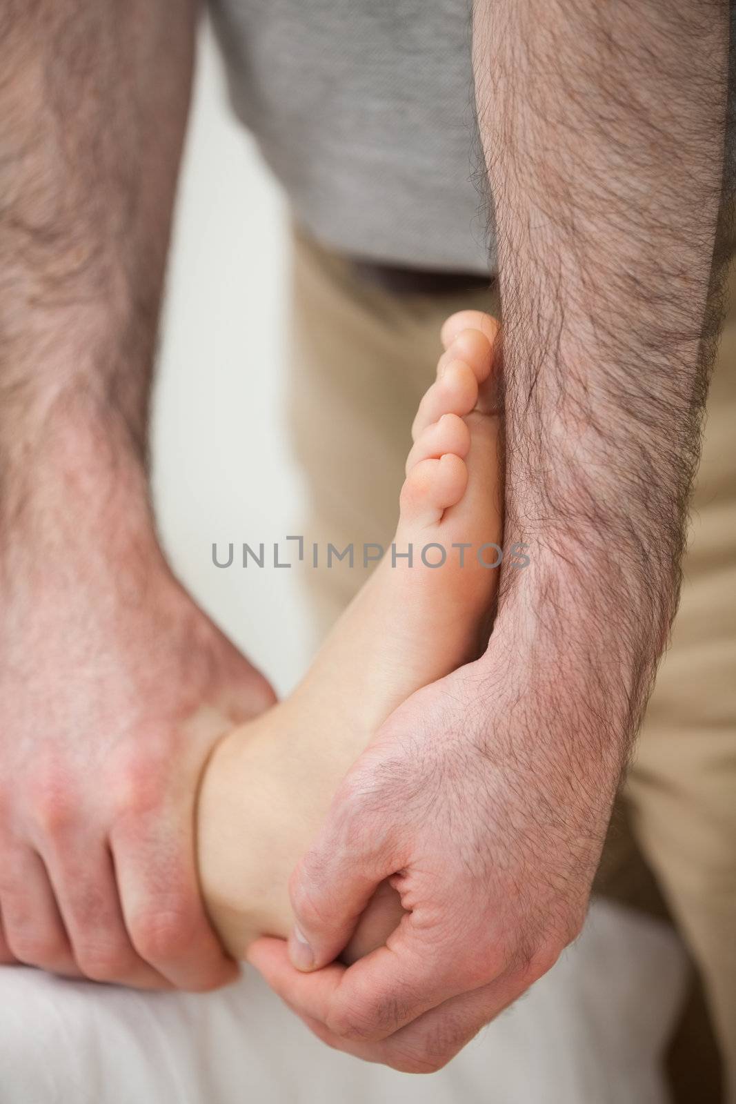 Doctor making a joint mobilisation on the ankle of a woman in a room