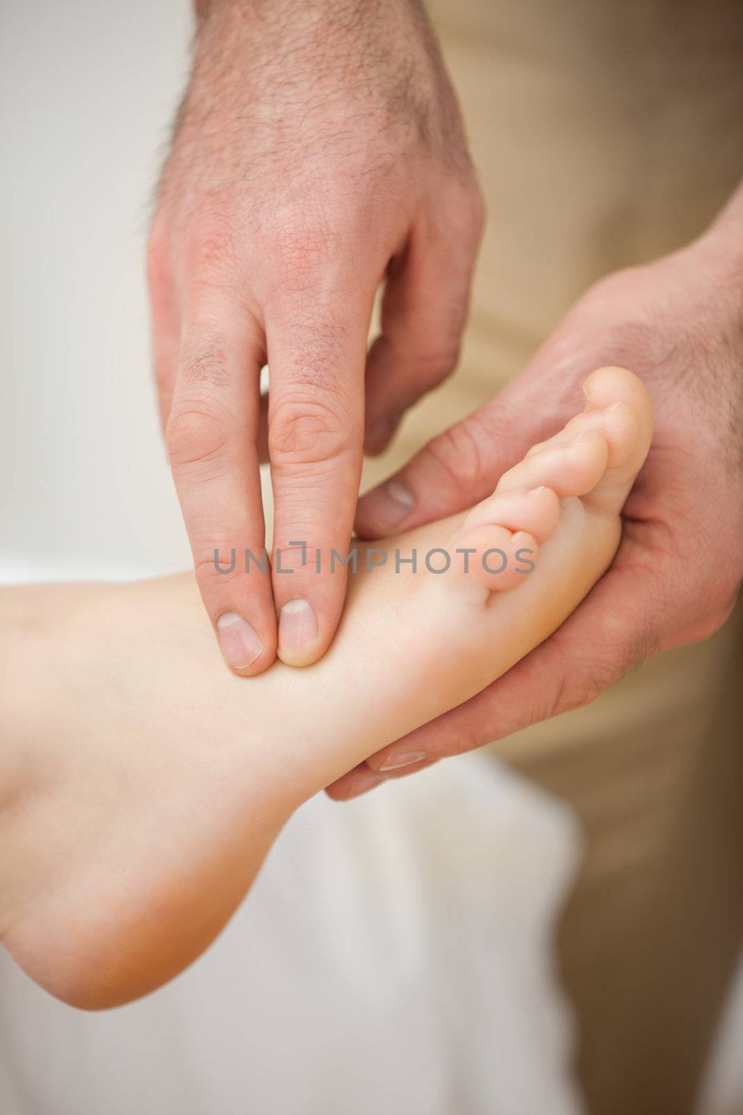 Two fingers palpating the muscles of a foot indoors