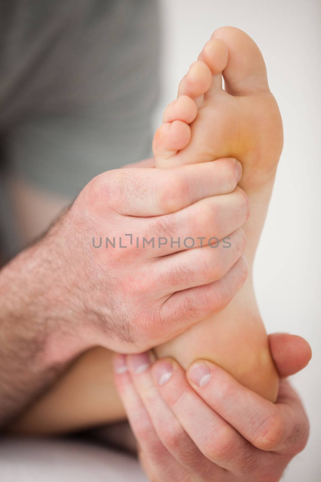 Hands of a practitioner holding a barefoot in a room