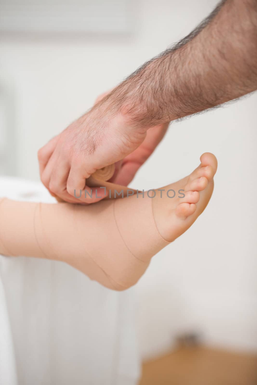 Doctor bandaging an ankle by Wavebreakmedia