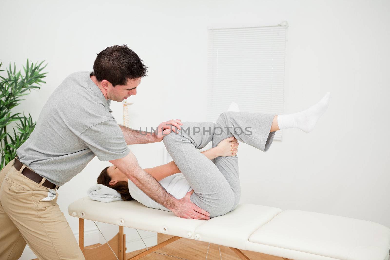 Physiotherapist pushing the leg of a woman on the side in a medical room