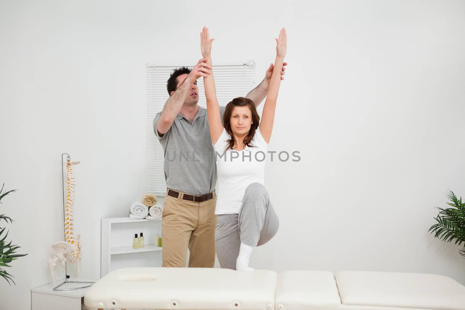 Brunette doing stretching exercises with a physiotherapist in a room
