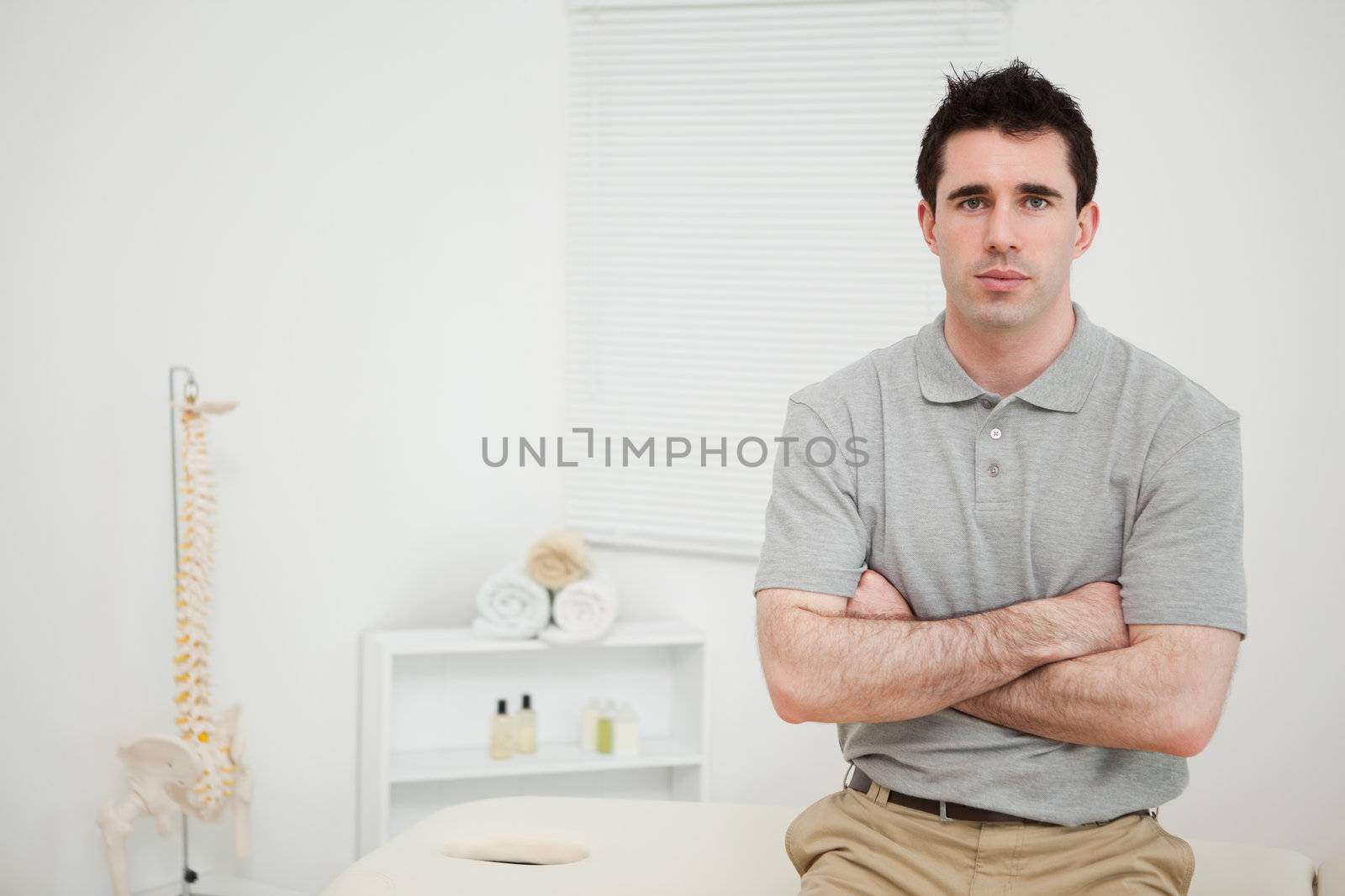 Serious physiotherapist crossing his arms in a medical room