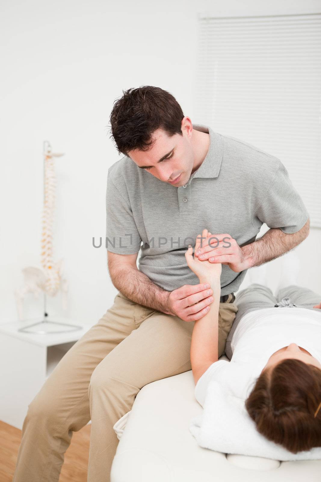 Serious physiotherapist moving the wrist of a woman by Wavebreakmedia