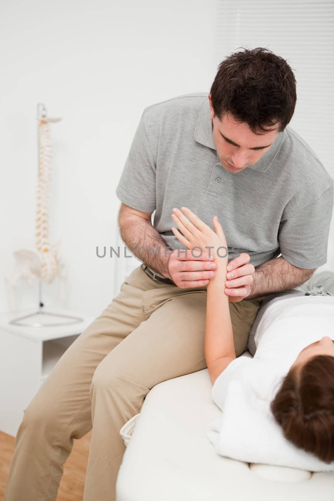 Physiotherapist placing his fingers on the hand of a patient in a room