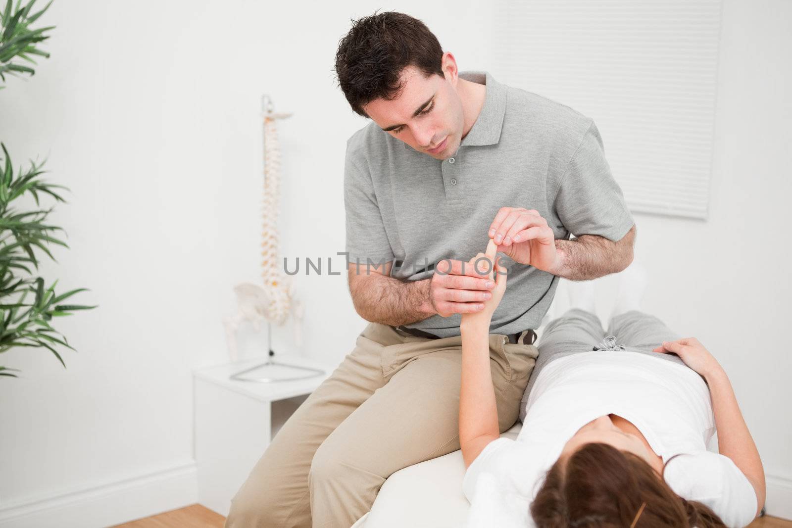 Physiotherapist moving the forefinger of a patient in a room