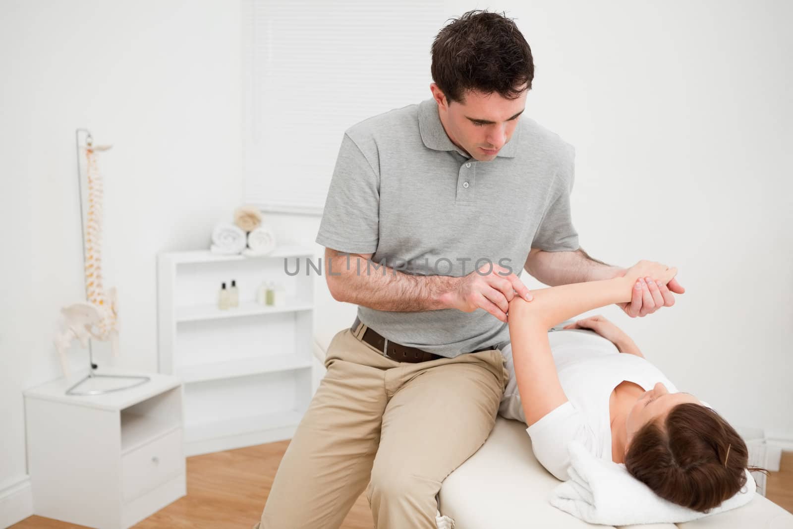 Serious doctor looking at the arm of a patient in a room