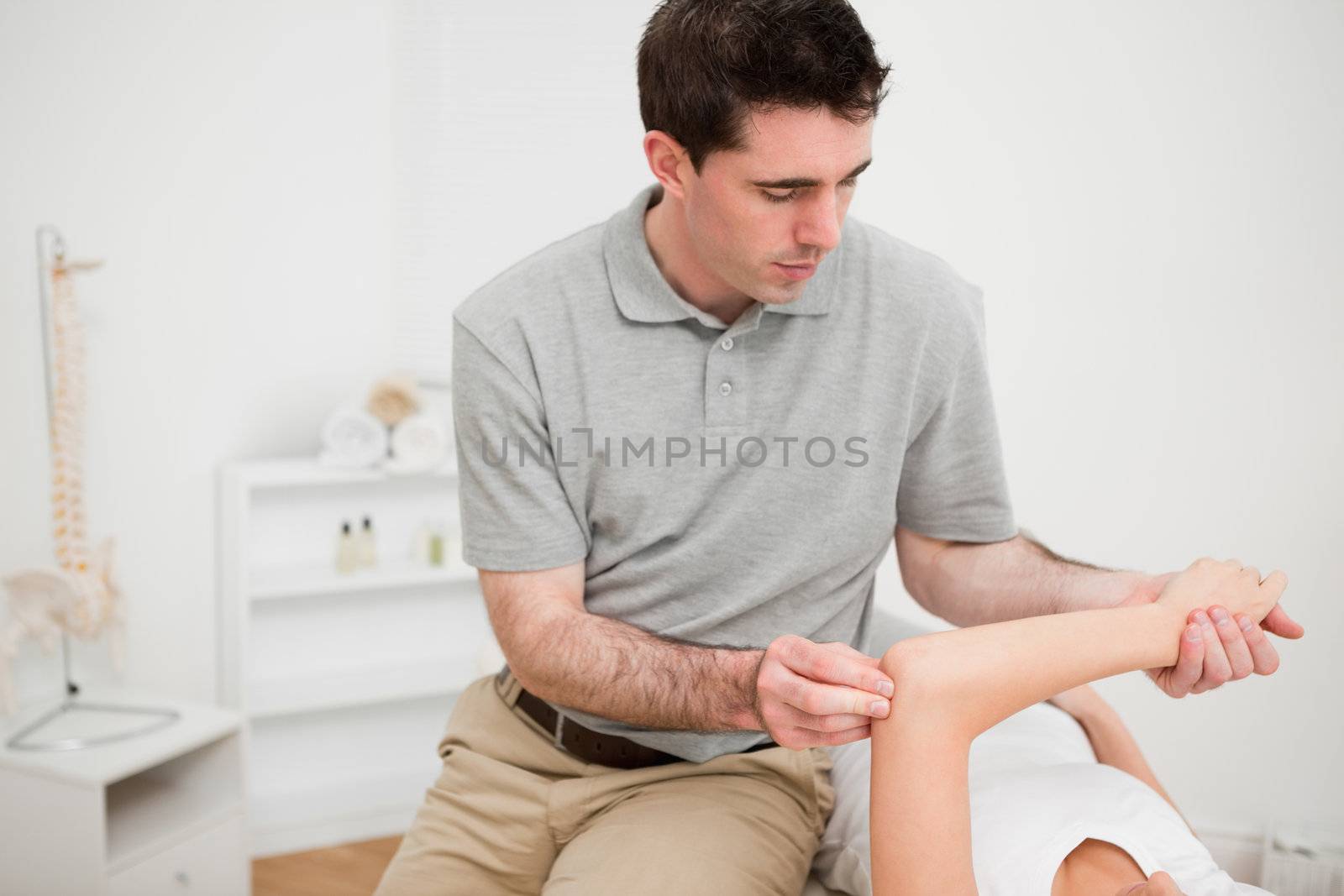 Serious brunette physiotherapist holding the arm of a woman by Wavebreakmedia