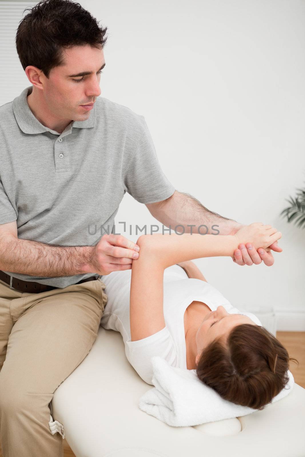 Osteopath stretching the arm of his patient in a medical room