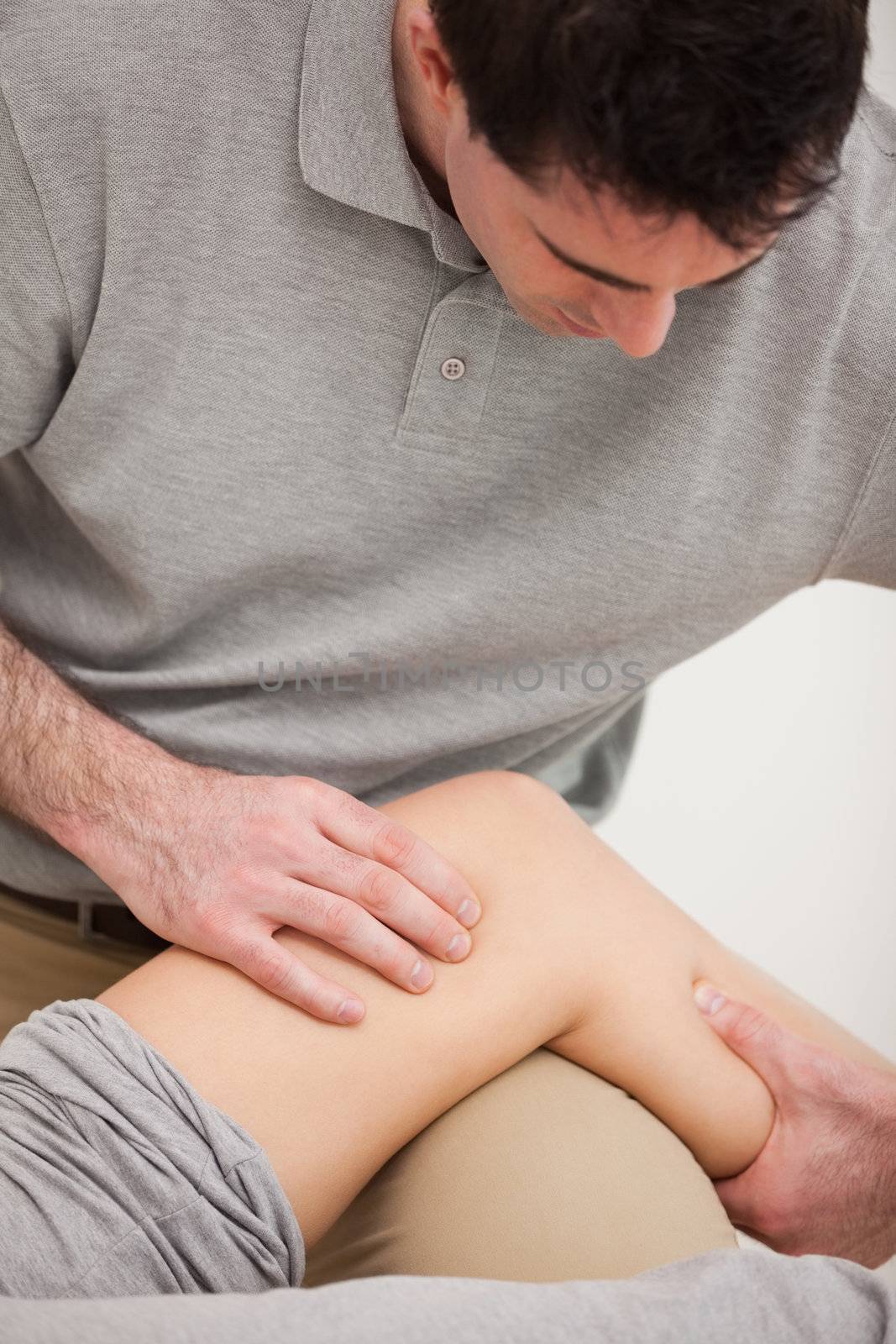 Physiotherapist looking at the knee of his patient indoors