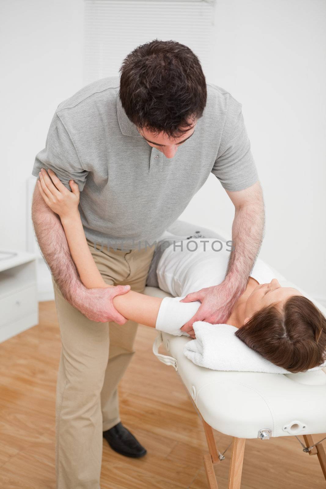 Osteopath working on a shoulder of a patient in a room