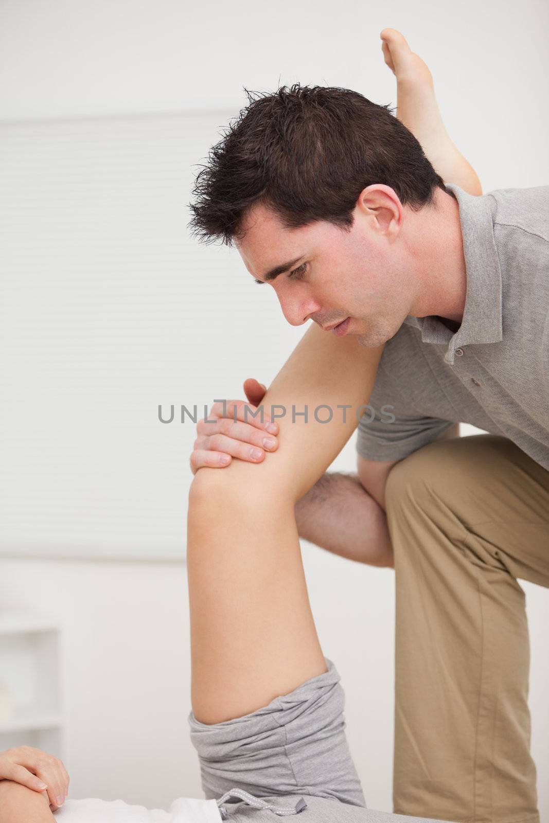 Serious osteopath holding a leg in a room