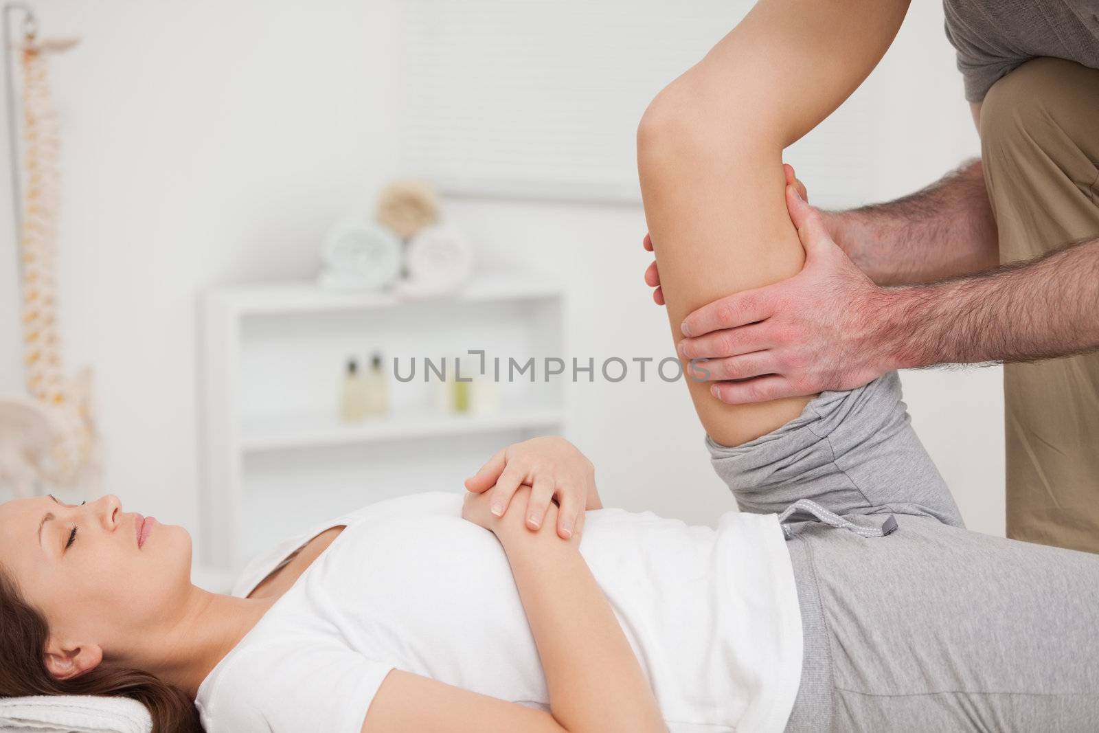 Physiotherapist holding the thigh of a patient in a room