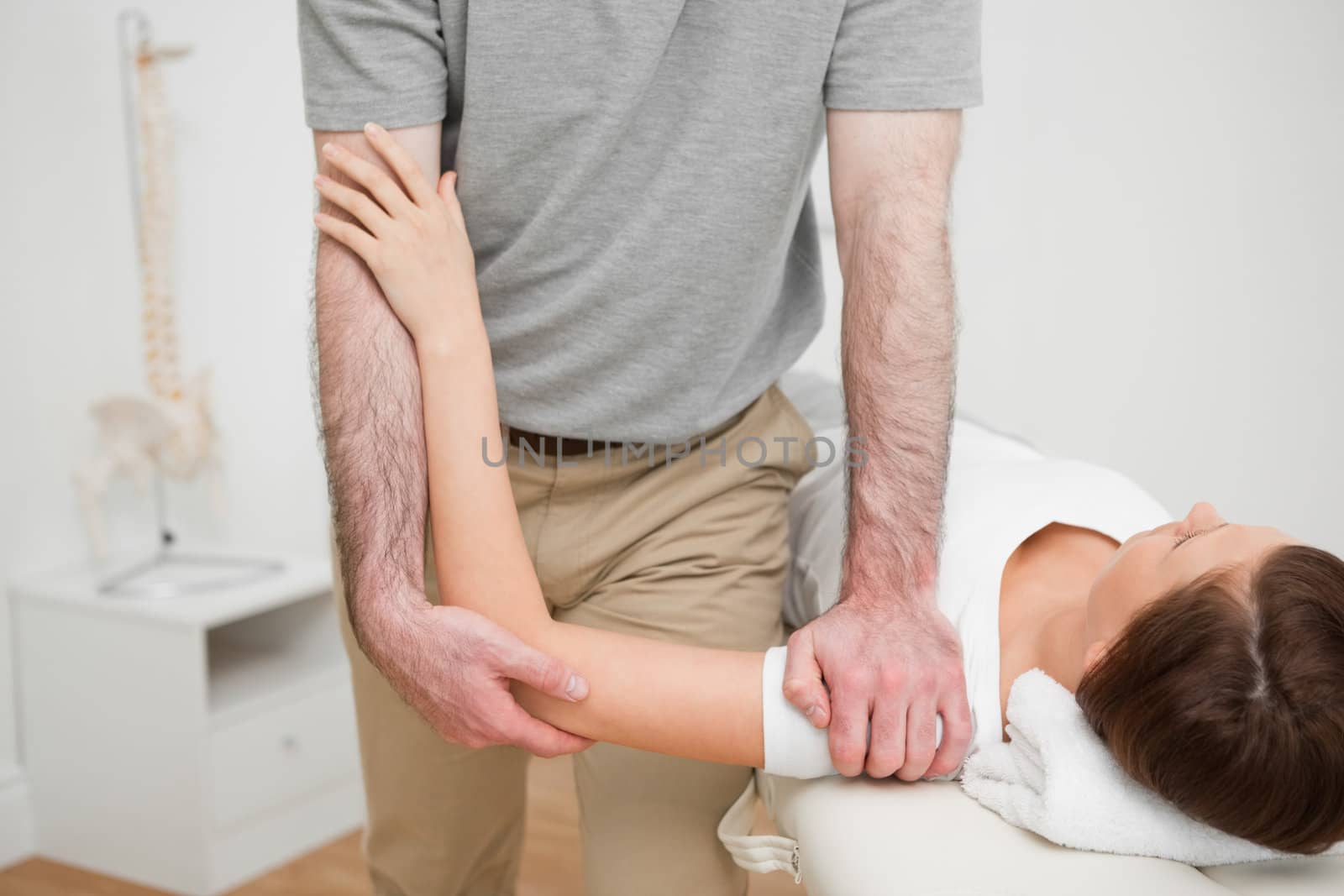 Physiotherapist pressing the shoulder of a woman in a medical room