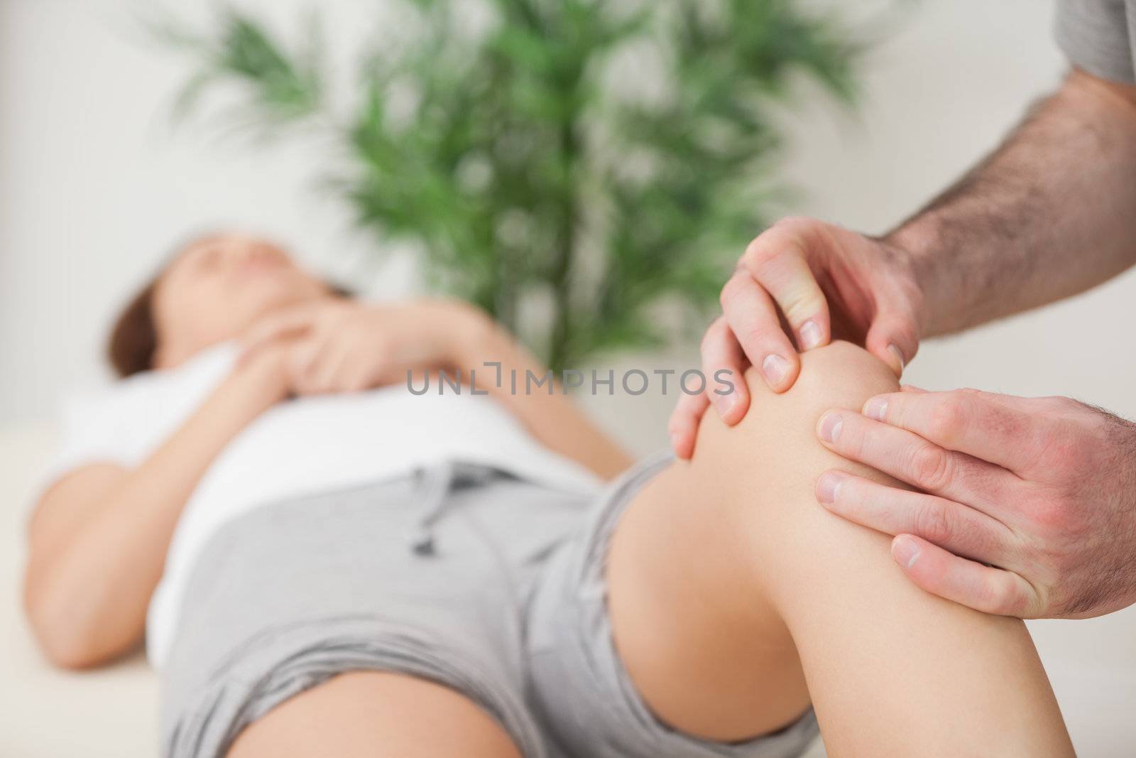 Knee of a woman being touched by a doctor in a room