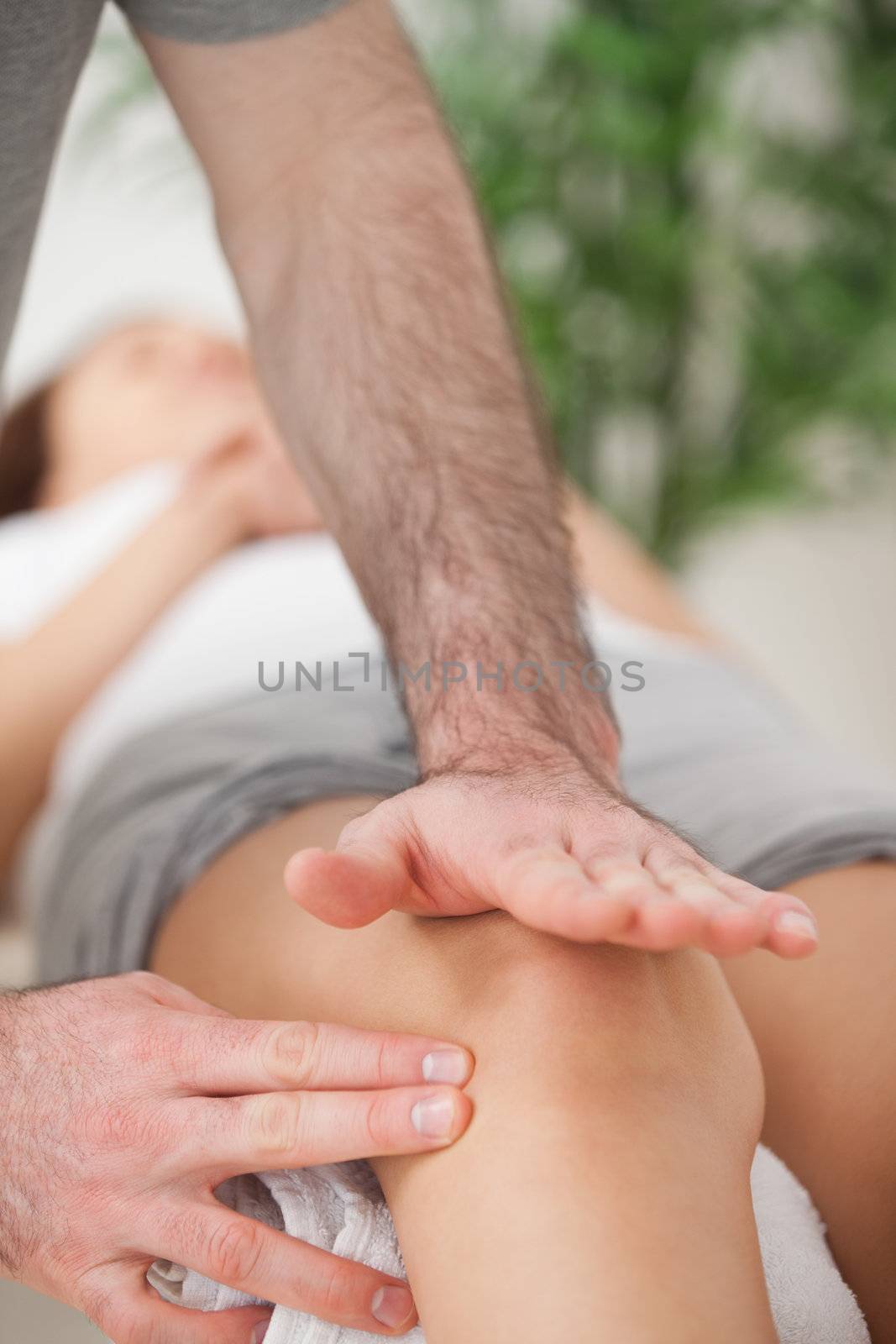 Physiotherapist using his hand palm to massage a knee indoors
