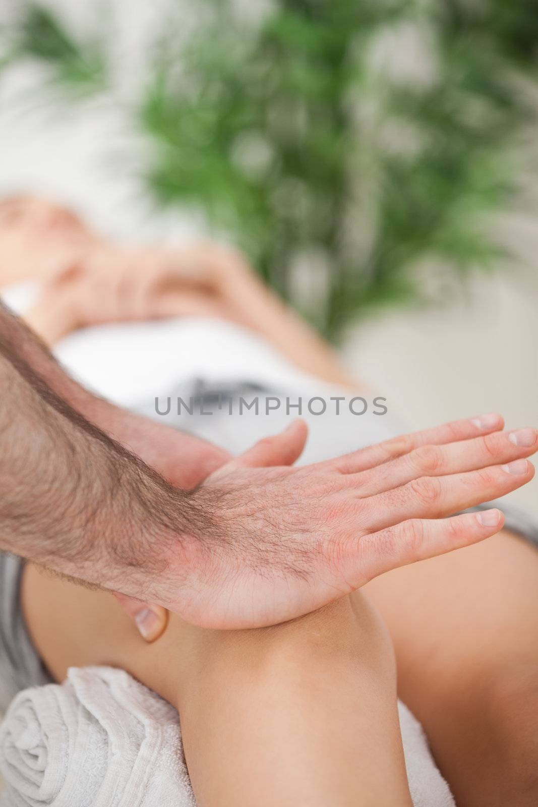 Osteopath using his hand palm to massage a knee in a medical room