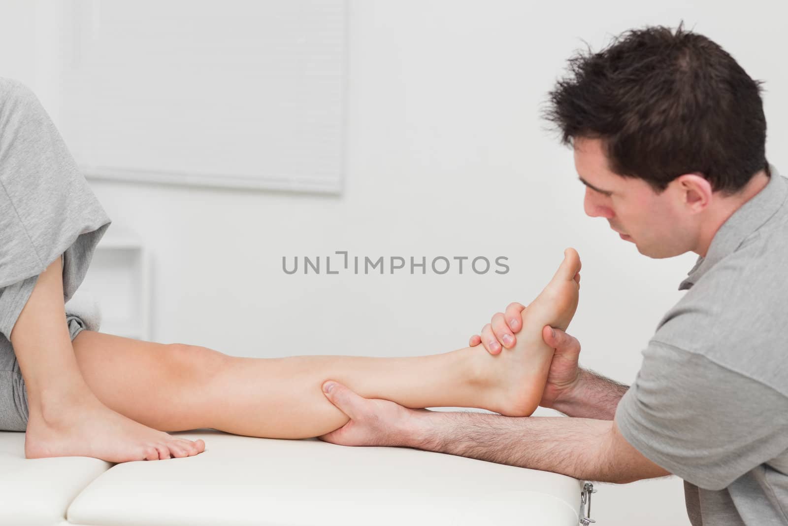 Serious doctor massaging a calf on a medical table by Wavebreakmedia