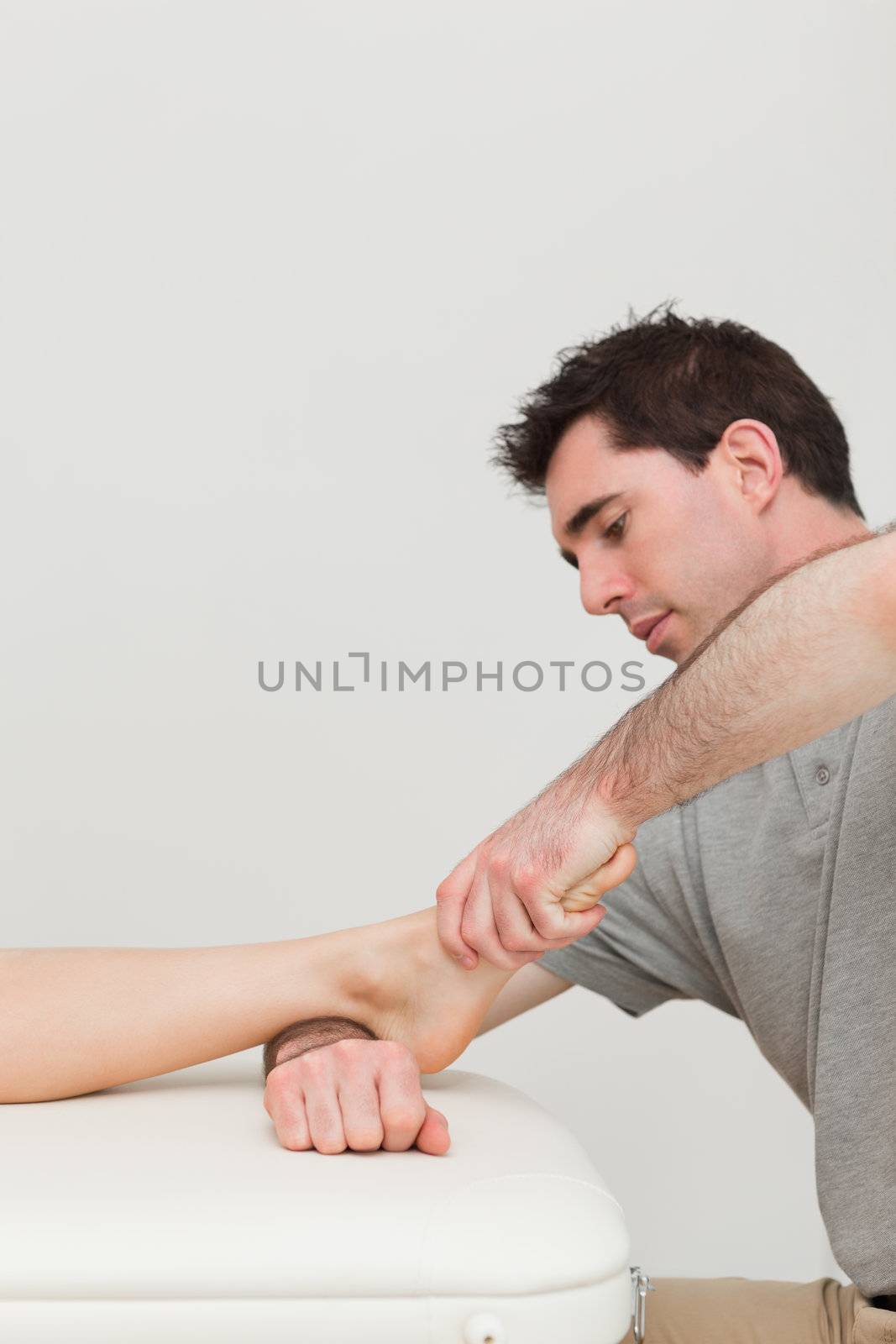 Serious practitioner holding the foot of a patient indoors