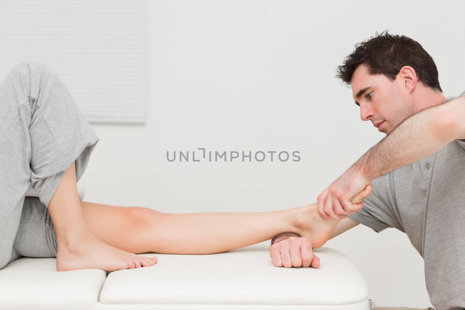 Serious doctor stretching the foot of his patient in a room