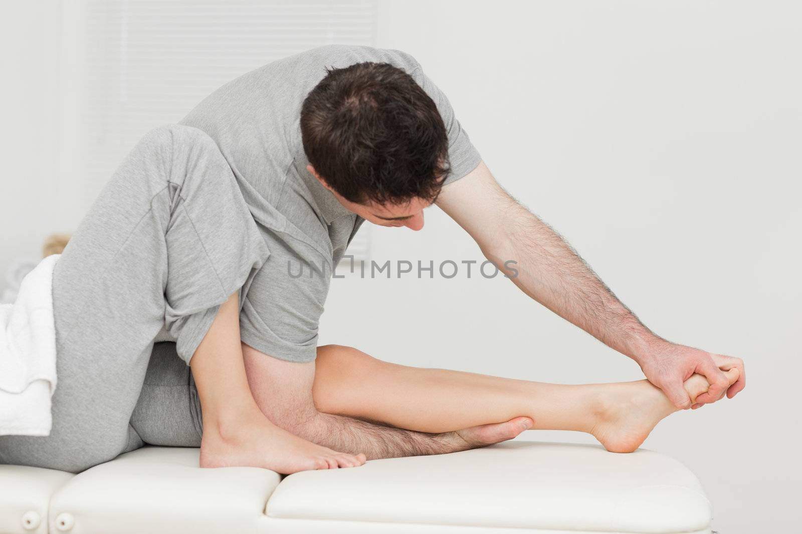 Brunette osteopath stretching a foot in a medical room