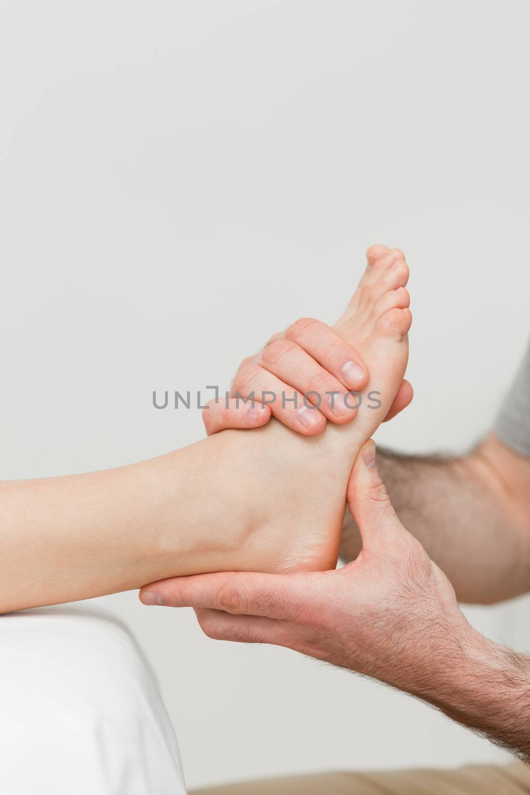 Hands of a physiotherapist massaging a foot in a room