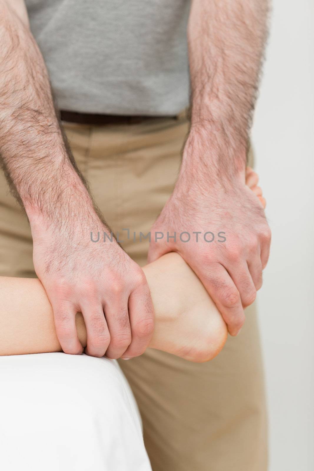 Osteopath manipulating the ankle of a patient by Wavebreakmedia