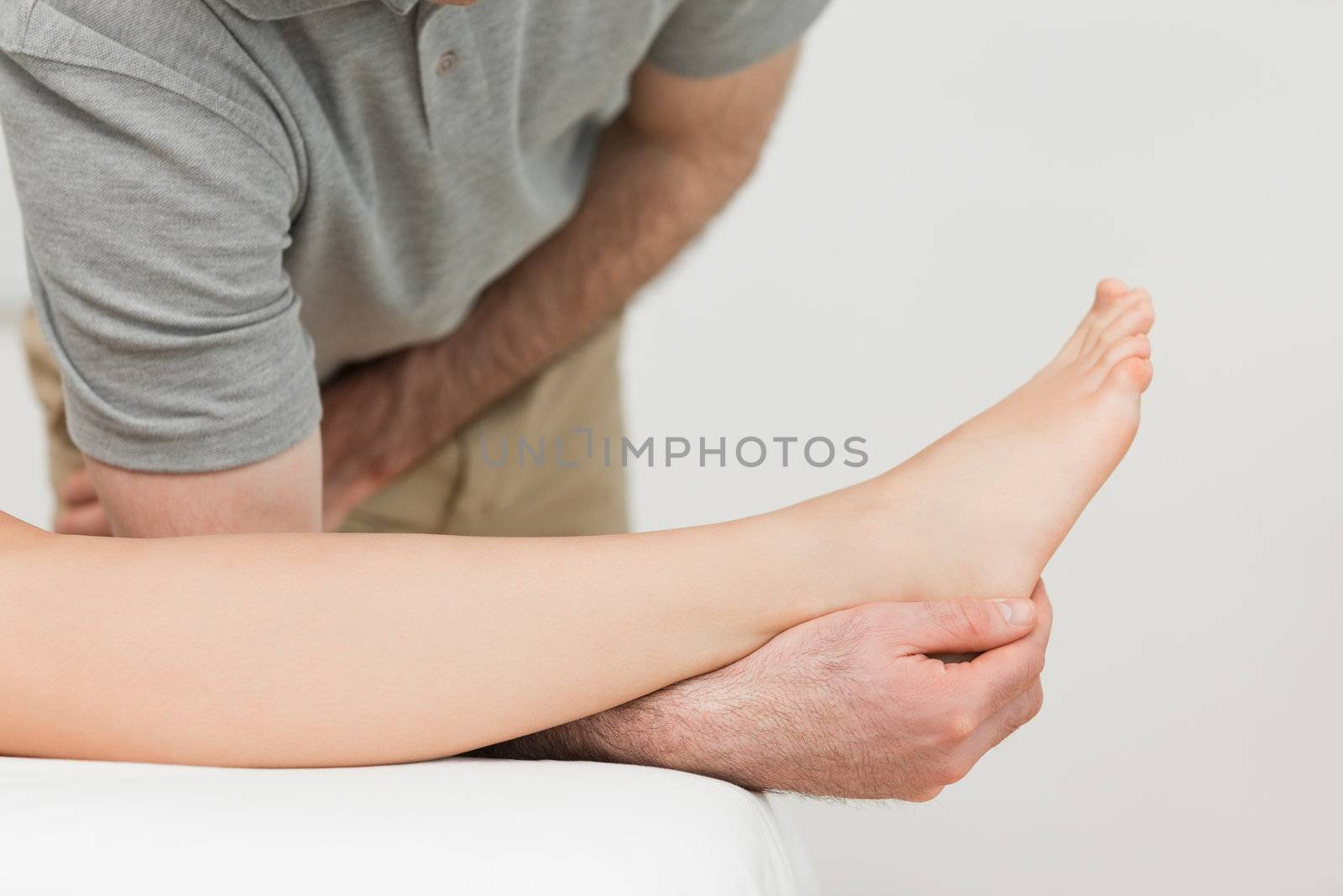Serious physiotherapist working on an ankle by Wavebreakmedia