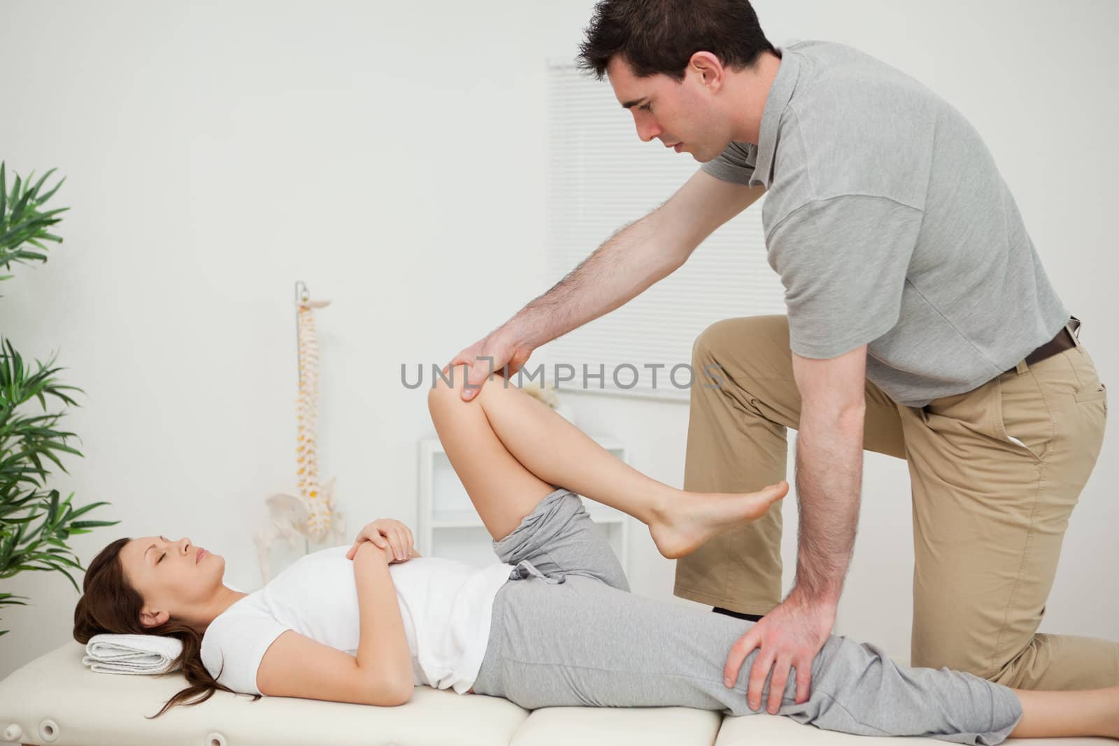Serious doctor stretching the leg of a woman in a room
