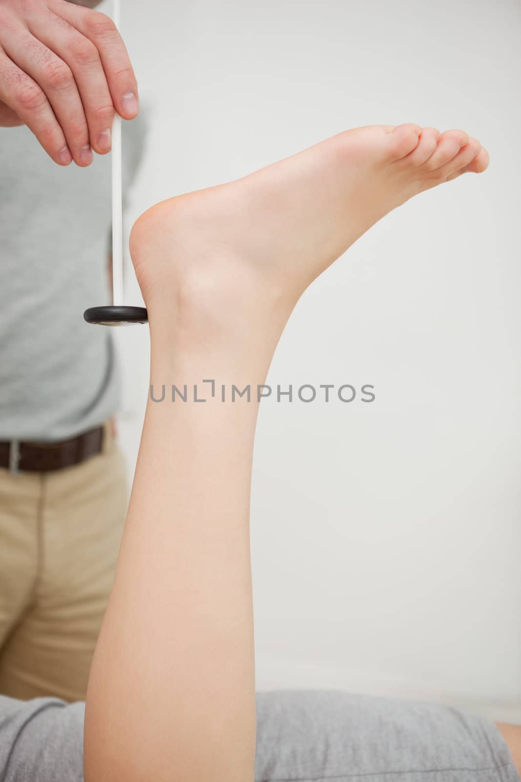 Doctor checking the reflexes of the ankle of a patient in a medical room