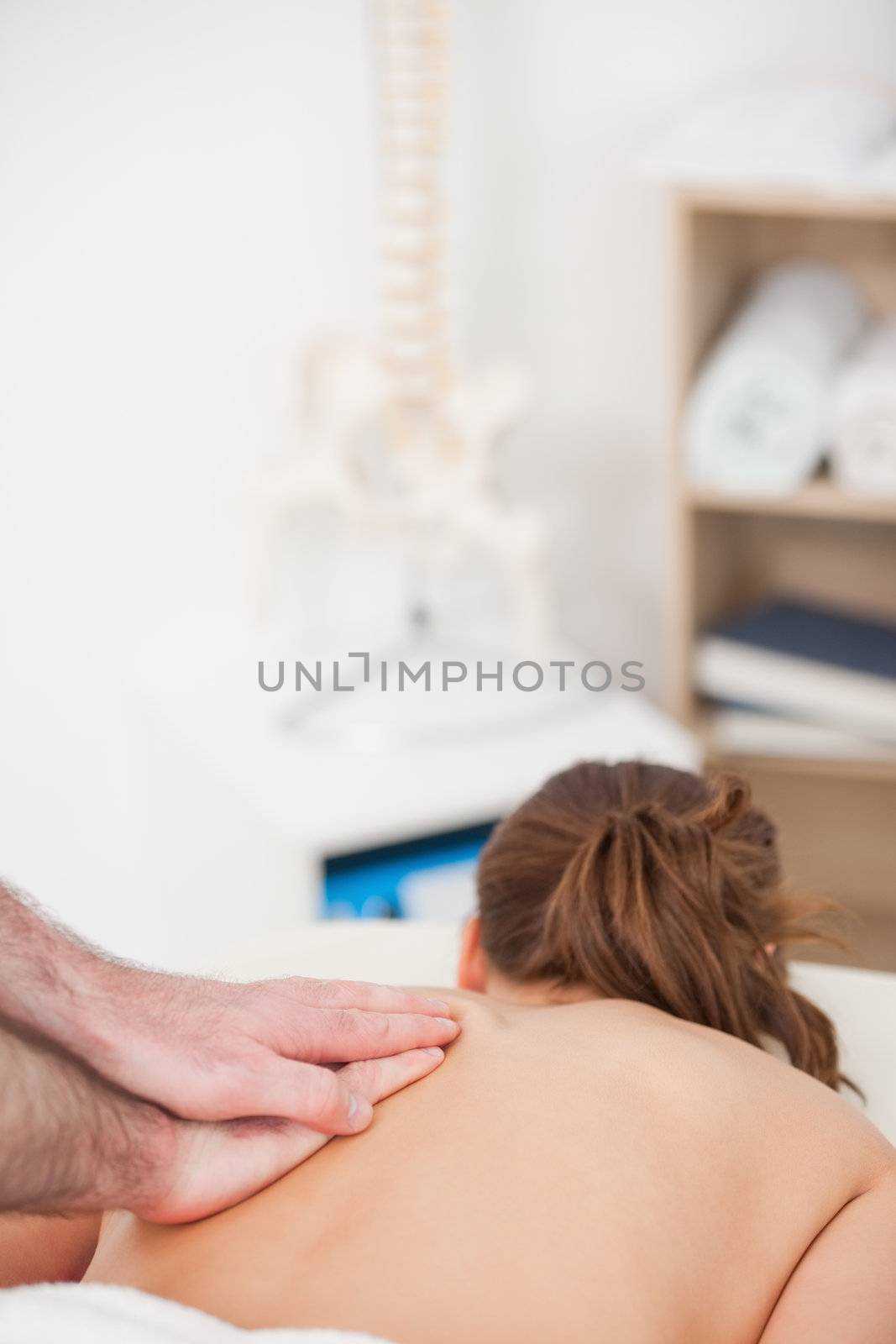Back of the woman being massaged by a masseur in a room