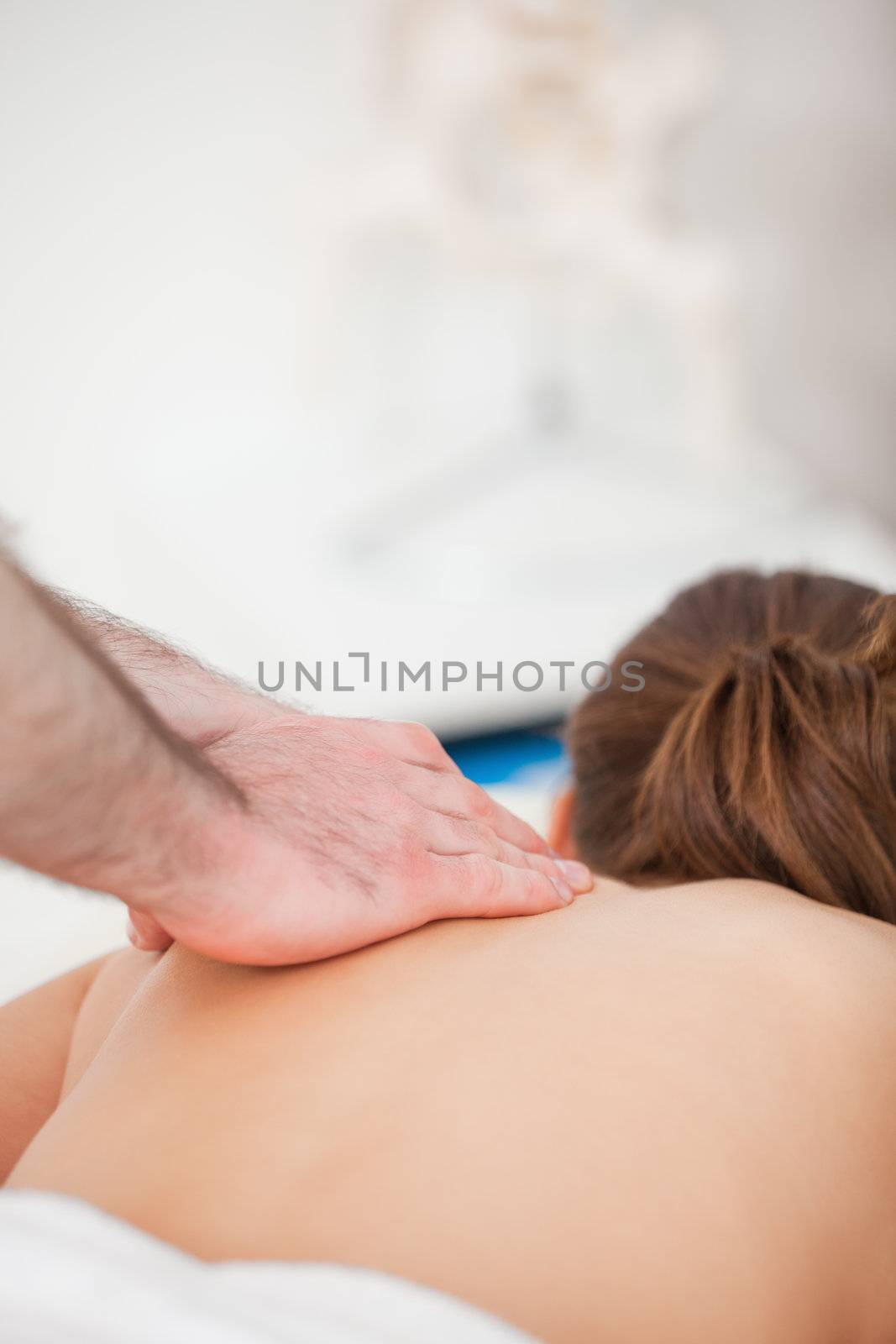Chiropractor massaging the back of his patient indoors