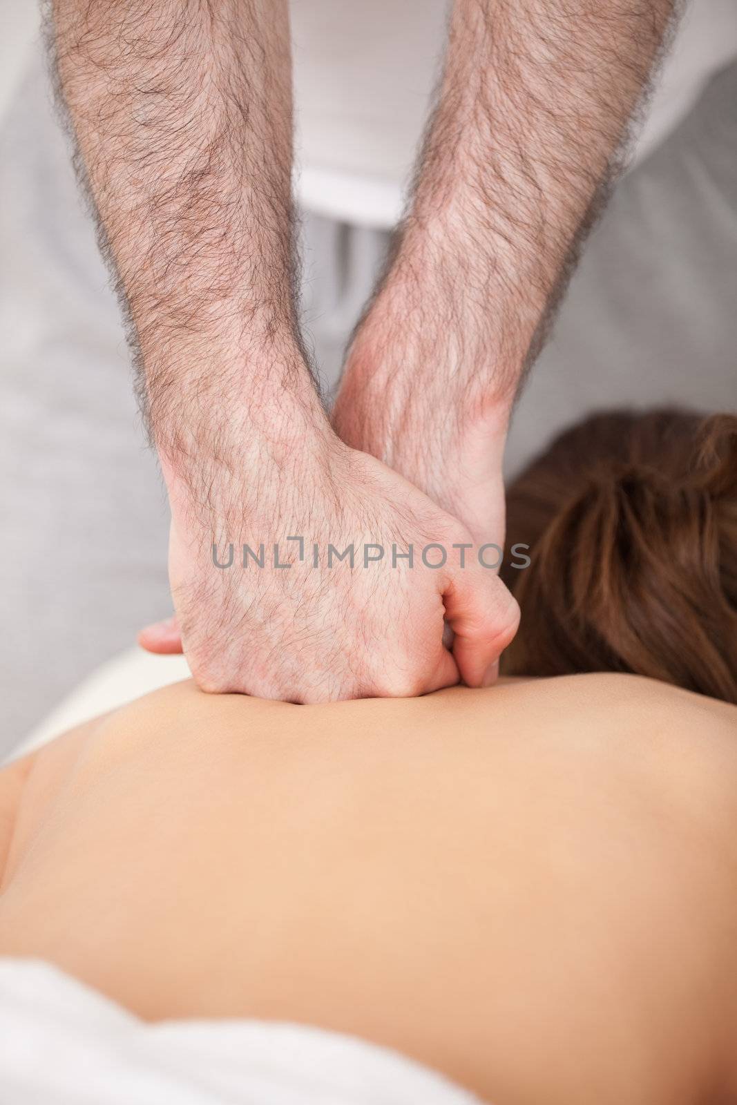 Doctor massaging the back of his patient while using the back of his hand in a room