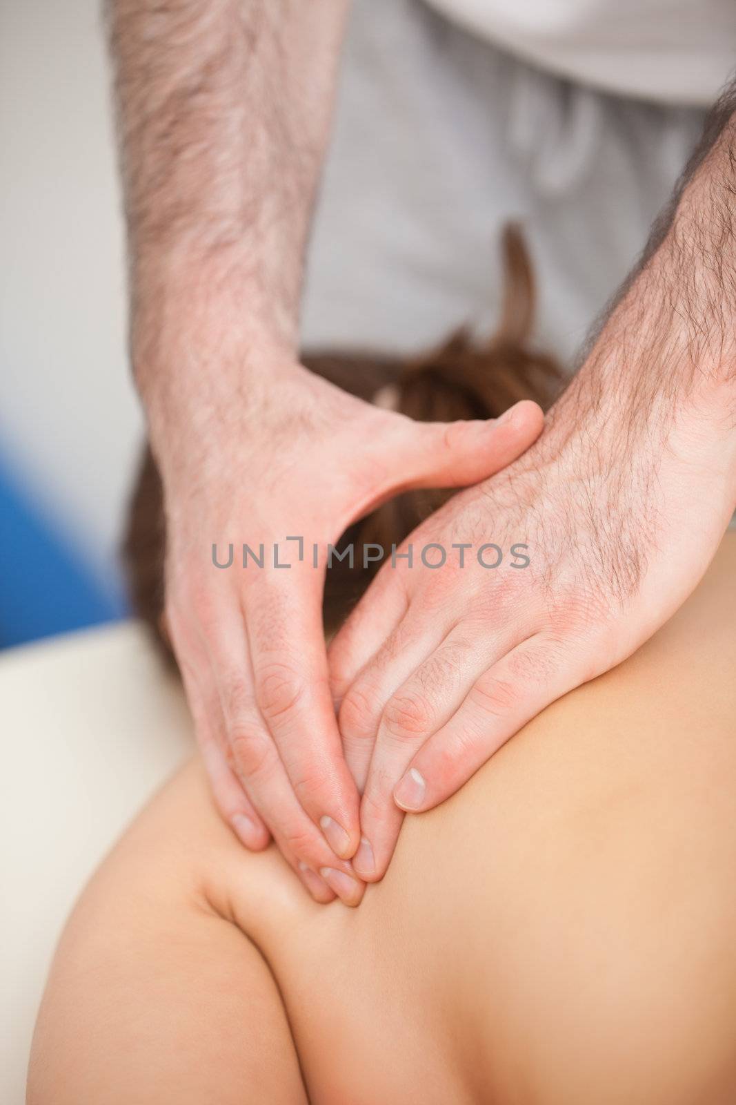 Doctor pressing the side of the back of his patient while standing indoors