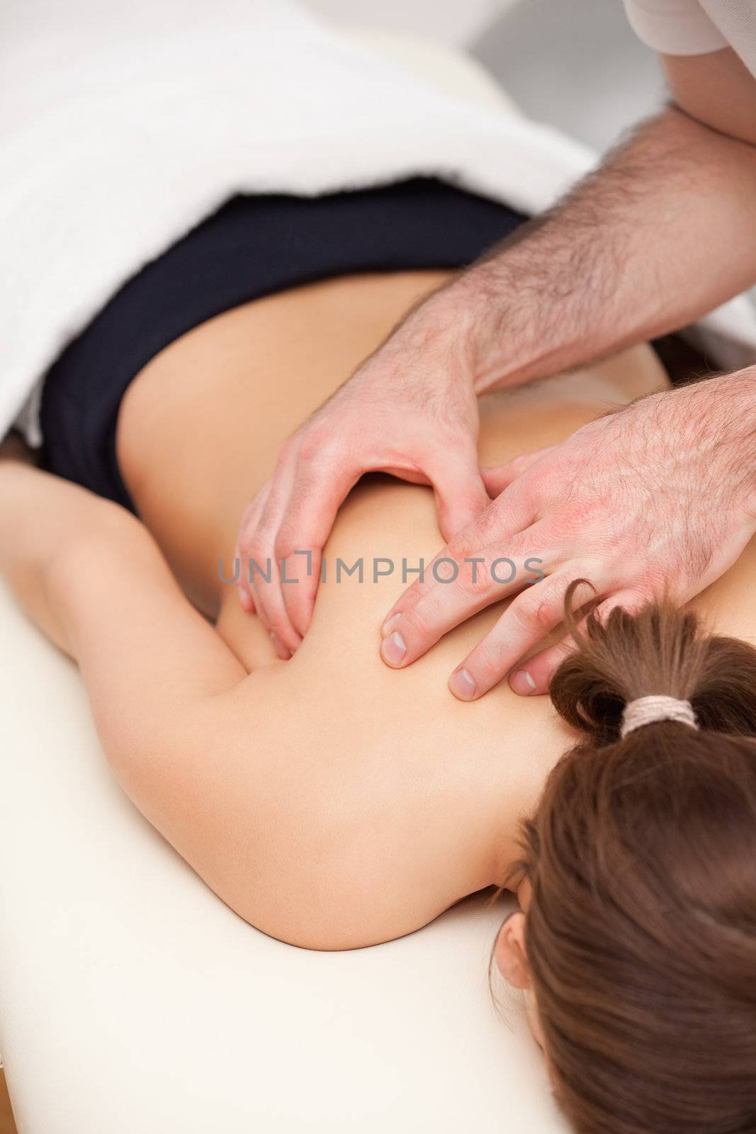 Woman lying on the table while being massaged in a room
