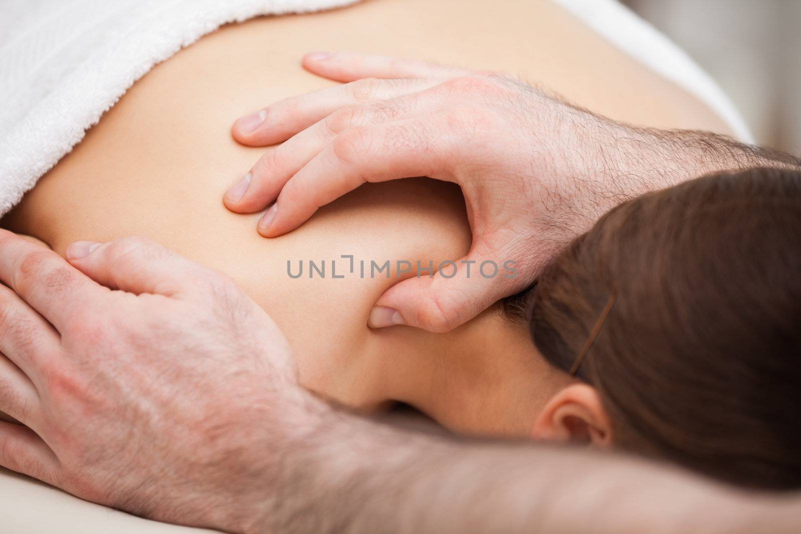 Osteopath massaging his patient while pressing his tumb in a room