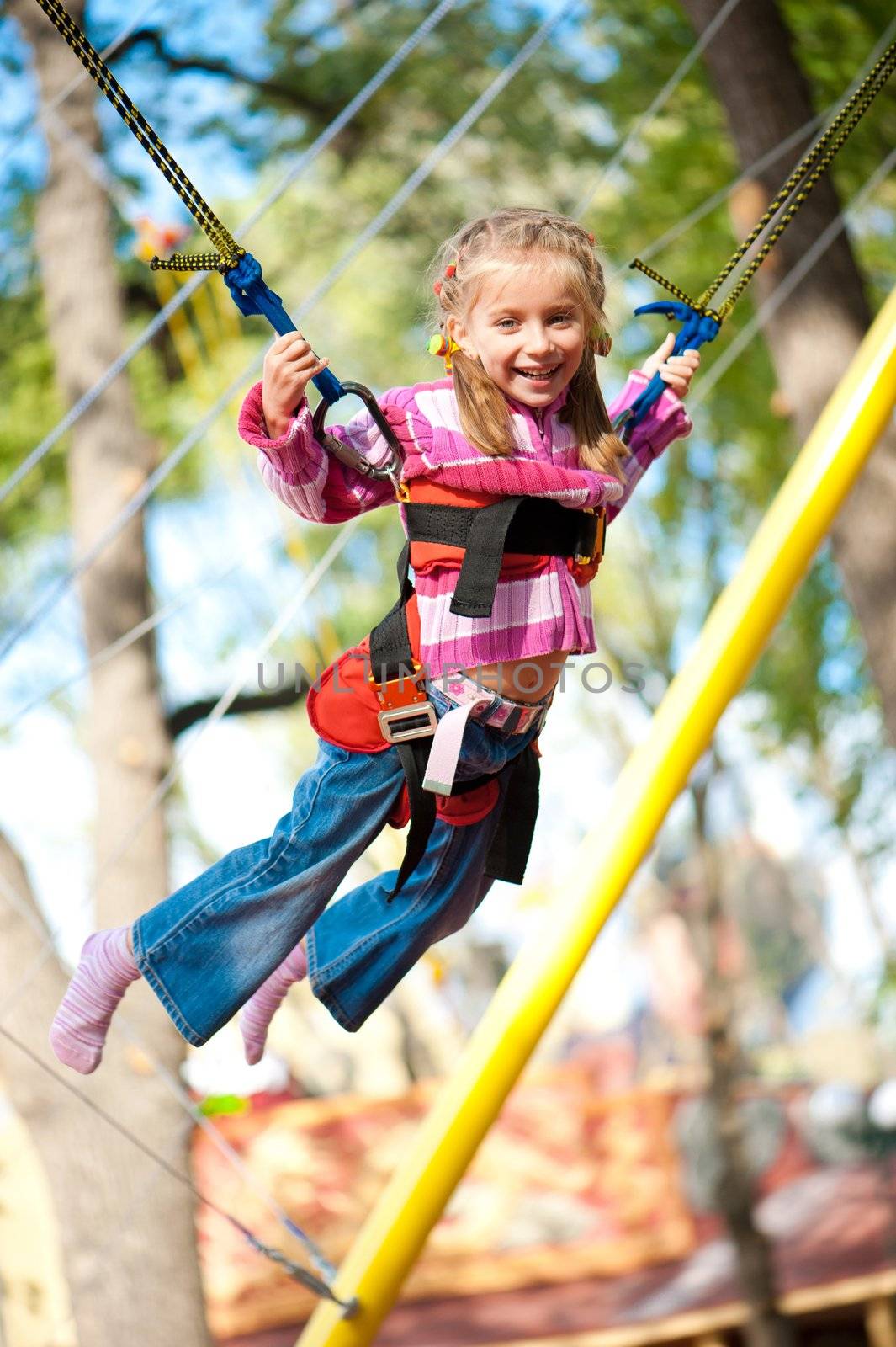 Little girl jumping on the trampoline with rubber bands