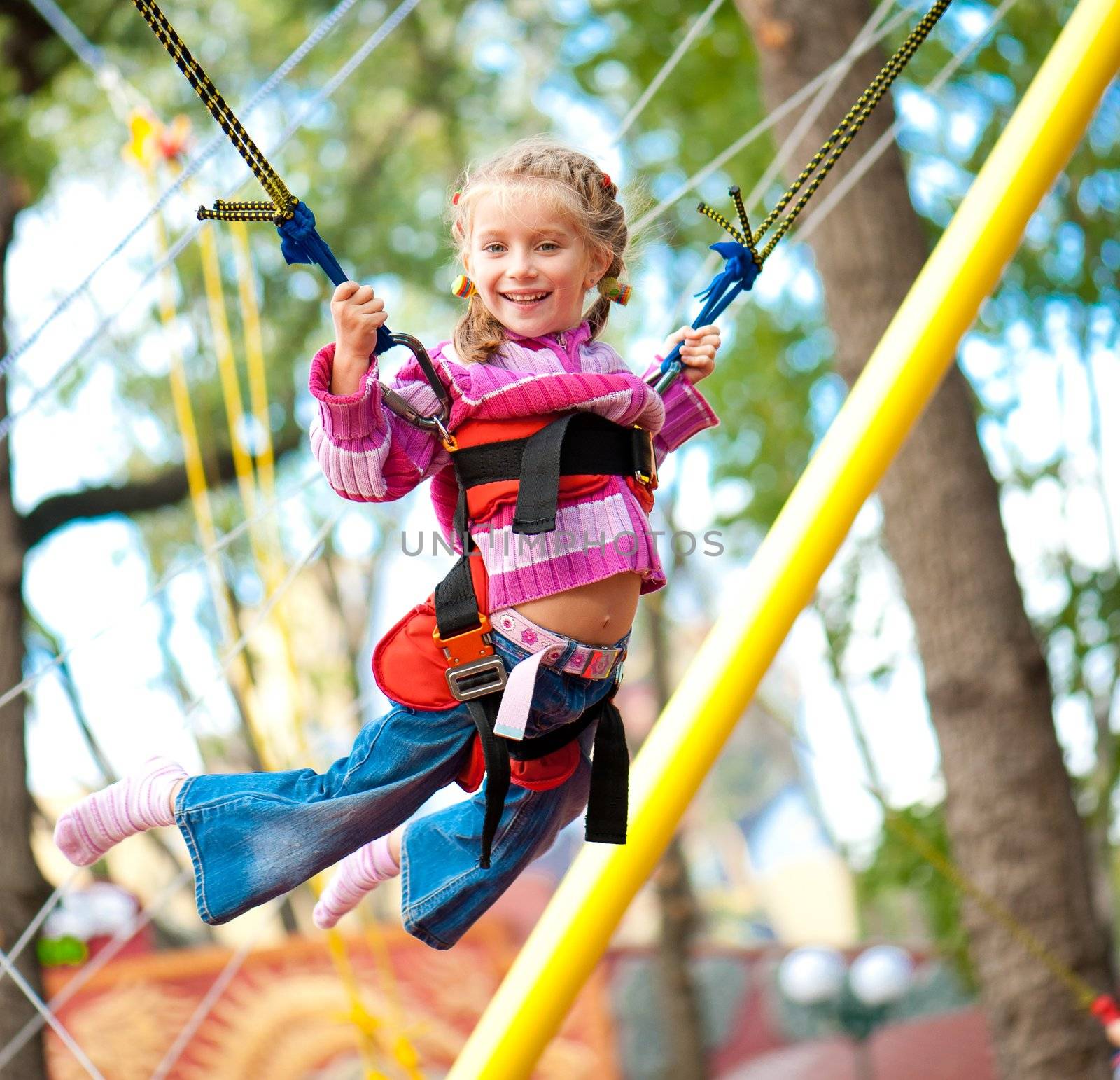 Little girl jumping on the trampoline with rubber bands